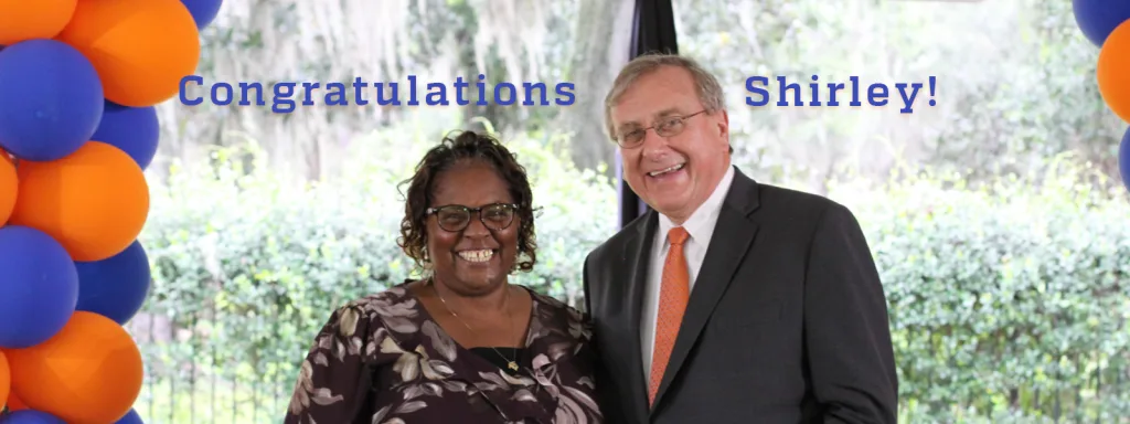 Shirley Robinson and Dr. Fuchs posing together with balloons in the background with the text "Congratulations Shirley!" written around them.