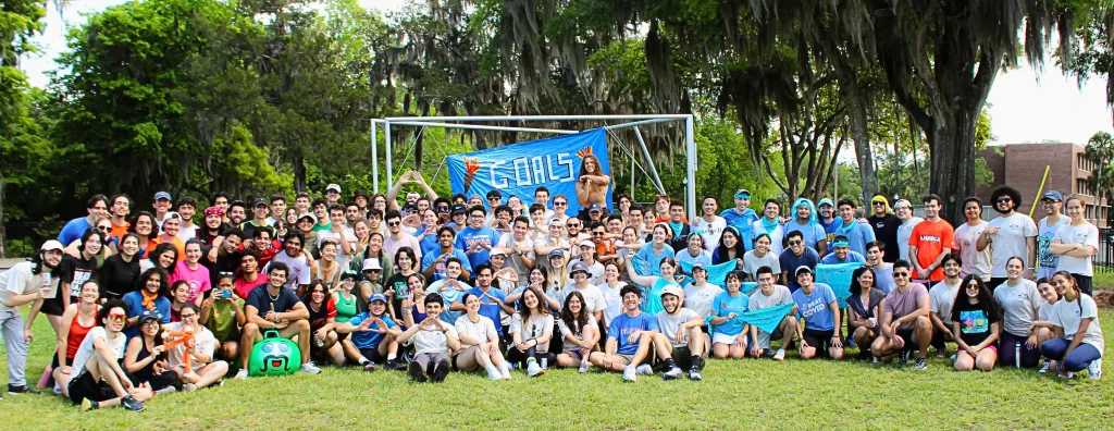 Large group of students smile in front of banner that states "goals"
