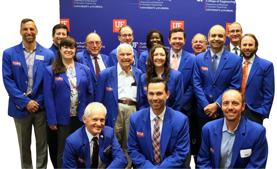group of people smiling in blue jackets with the letters "MAE" on the right side of each jacket.