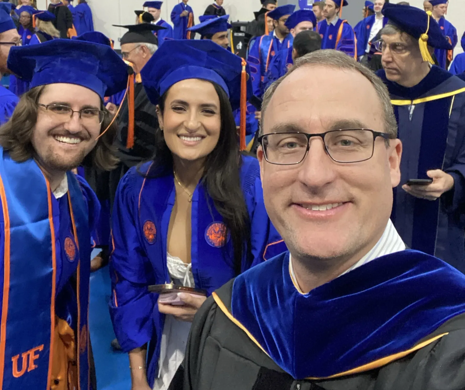 Douglas Spearot taking a selfie with two graduates.