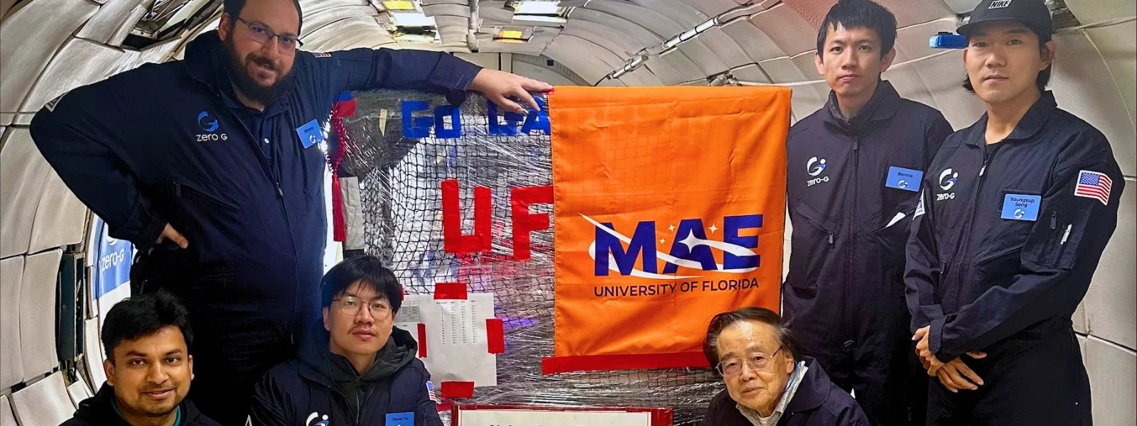 Group- people in uniforms with "zero g" logo stand next to equipment with the letters "UF" and a banner that reads "MAE University of Florida".